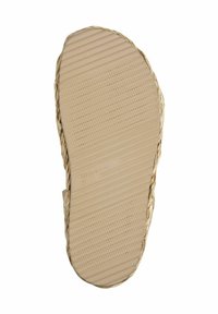 Sole piatta di colore marrone chiaro, con superficie testurizzata e scanalature orizzontali. I bordi presentano un design intrecciato. Caratterizzata da un marchio impresso sul plantare.