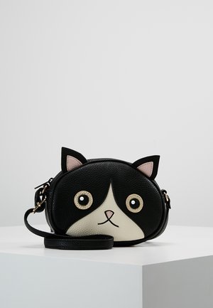 Kleine schwarz-weiße Umhängetasche in Form eines Katzenkopfs mit Ohren, runden Augen, rosa Nase und einfachem Riemen auf weißer Oberfläche.