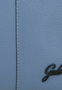 Borsa in pelle azzurro chiaro con finitura strutturata, caratterizzata da cuciture bianche a contrasto e un accento con logo nero.