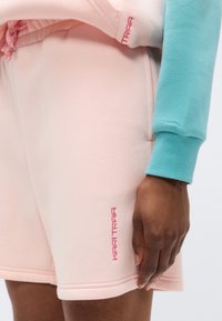 Ροζ βαμβακερά σορτς με πλαϊνές τσέπες και ροζ κεντημένο λογότυπο. Ομαλή υφή με ελαστική μέση και άνετη εφαρμογή.