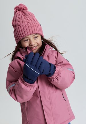 Roze geïsoleerde jas met strakke manchetten, gecombineerd met een ribbeltrui roze gebreide beanie met een pompon, en marineblauwe handschoenen.