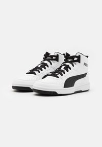 Höga sneakers med en vit läderöverdel och svarta accenter, texturerade paneler, perforeringar och svarta snören. PUMA-logotyp på sidan.