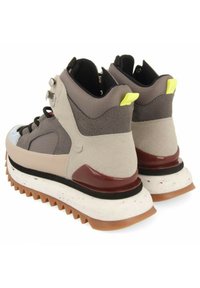 Zapatillas altas con un upper de ante marrón y gris, acentos en negro y gris, una entresuela blanca moteada y una suela texturizada de goma.