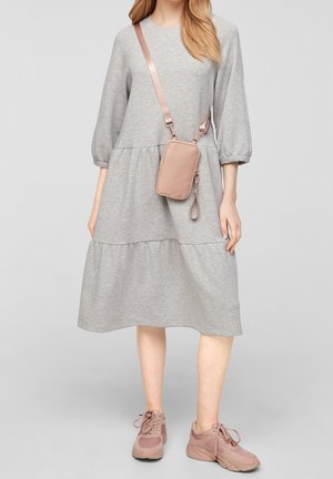Abito di cotone grigio con maniche tre quarti e design a strati, abbinato a una borsa a tracolla rosa e sneakers abbinati.