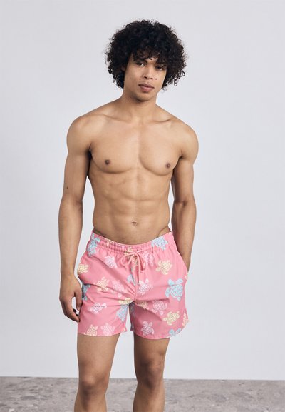 Costume de baie roz cu un model de țestoasă în culori galbene și albastre. Talie elastică cu șnur de ajustare. Material ușor, lungime deasupra genunchiului.