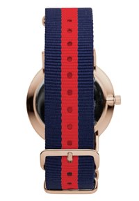 Marinefarget stoffrem med en rød stripe, med en urkasse i gullfarge og metallspenne. Rund klokke med en svart urskive på undersiden.