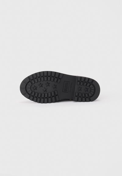 Semelle de chaussure en caoutchouc noir avec un motif de semelle en étoile et des rainures pour l'adhérence. Design plat, texture robuste et matériau durable.