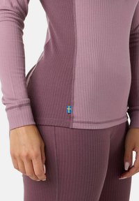 Prążkowany, długi rękaw top i legginsy w różnych odcieniach fioletu. Posiada mały emblemat szwedzkiej flagi na boku topu.