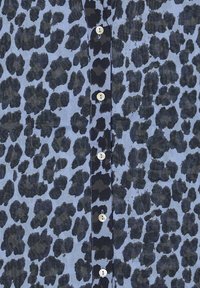 Overhemd met knopen, met een blauwe achtergrond en een zwart luipaardprintpatroon. Heeft een rij witte knopen aan de voorkant.