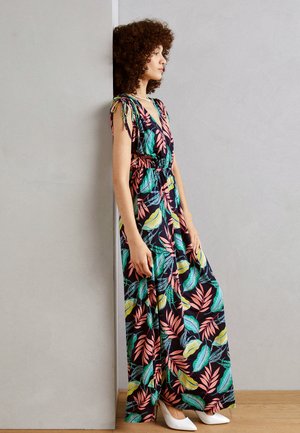 Abito maxi con uno sfondo scuro e vivaci motivi di foglie tropicali in rosa, verde e giallo. Ha una vita cintrata e spalline annodate.