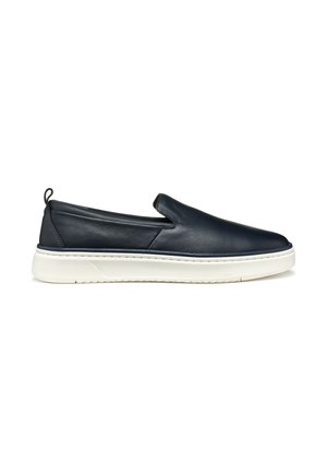Zapato deslizante de cuero azul marino con suela de goma blanca. Presenta una textura suave y un diseño minimalista con paneles laterales elásticos para facilitar su colocación.