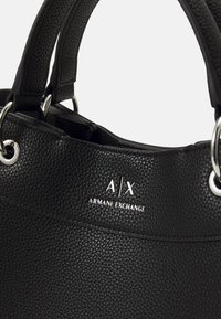 Schwarze, strukturierte Handtasche mit zwei Griffen, ausgestattet mit silberfarbenen Beschlägen, geprägtem Logo und einer runden Form. Das Design beinhaltet eine strukturierte Öffnung.