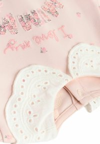 Rosa Baumwoll-Overall mit floraler Stickerei in Pastellfarben, Spitze mit gewellten Kanten und Druckknopfverschluss am Boden.