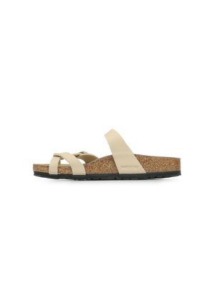 Sandale beige avec des sangles croisées, semelle en liège et semelle en caoutchouc noir. Design minimaliste, construction légère et flexible.