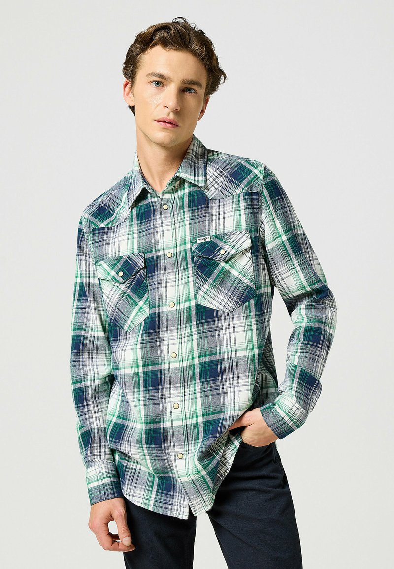 Koszula w kratę z długim rękawem w zielonym, granatowym i białym kolorze, z dwoma kieszeniami z przodu, kołnierzykiem w szpic i zapięciem na guziki. Wykonana z lekkiego materiału.
