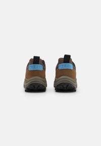 Brown and black athletic shoes with a textured suede upper, mesh panels, and a blue embossed logo on the heel. Thick black rubber soles.