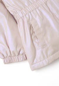 Giacca imbottita in tessuto lucido rosa chiaro, con polsini elasticizzati e una tasca laterale. Texture liscia e design aderente con chiusura a zip.