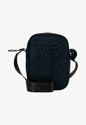 Petit sac bandoulière noir avec bandoulière réglable, texte embossé "Superdry" et symbole circulaire de marque déposée à l'avant.