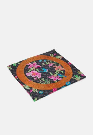 Sort firkantet stof med flerfarvet mønster af blomster og fugle, med en orange cirkel med præget tekst omkring midten.