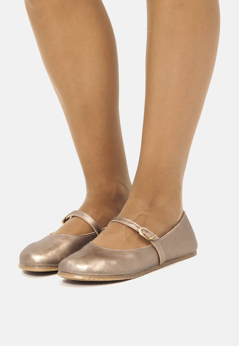 Ballerine in bronzo metallico con punta arrotondata, una sottile fascia sul dorso del piede e suola piatta. Texture liscia con una leggera lucentezza.