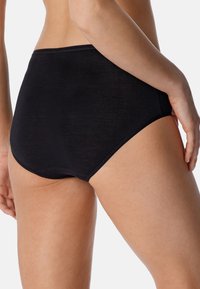 Mutandine nere a vita alta realizzate in un tessuto testurizzato e elastico. Presentano una cintura liscia e bordi senza cuciture per il massimo comfort.