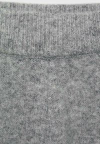 Tessuto lavorato a maglia grigio con texture a coste, caratterizzato da un aspetto morbido e fuzzy. Il materiale presenta leggere variazioni di ombreggiatura.