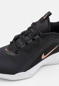 Musta urheilukengä, jossa on verkkoretki, teksturoidut yksityiskohdat, vaaleanpunainen Nike-logo ja vahvistettu kärki. Nauhoitusjärjestelmä turvallista istuvuutta varten.