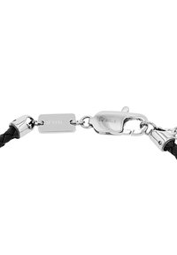 Pulsera de cuero trenzado negro con herrajes metálicos en plata, que presenta una etiqueta rectangular y un diseño de hebilla para un cierre seguro.