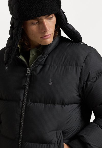 Čierna páperová bunda s prešívanou textúrou, so zipsom a náprsnými vreckami. Doplnková čierna čiapka s fleecovou podšívkou.