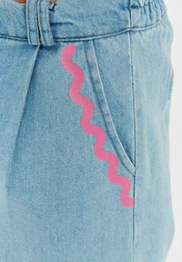 Svetlomodré denímové šortky s ružovým cik-cak vzorom pozdĺž vrecka. Majú elastický pás a voľný strih.