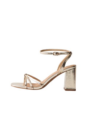 Gouden metalen sandaal met blokhak, dunne bandjes over de tenen en een verstelbare enkelband met gesp.