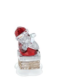 Figurita de cristal de Santa Claus con un gorro y traje rojos, subiendo por una chimenea de cristal con nieve blanca en la base.