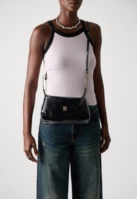 Crni kožni crossbody ruksak s teksturiranom završnom obradom, zlatnim metalnim detaljima, pravokutnim oblikom i dugom podesivom trakom.