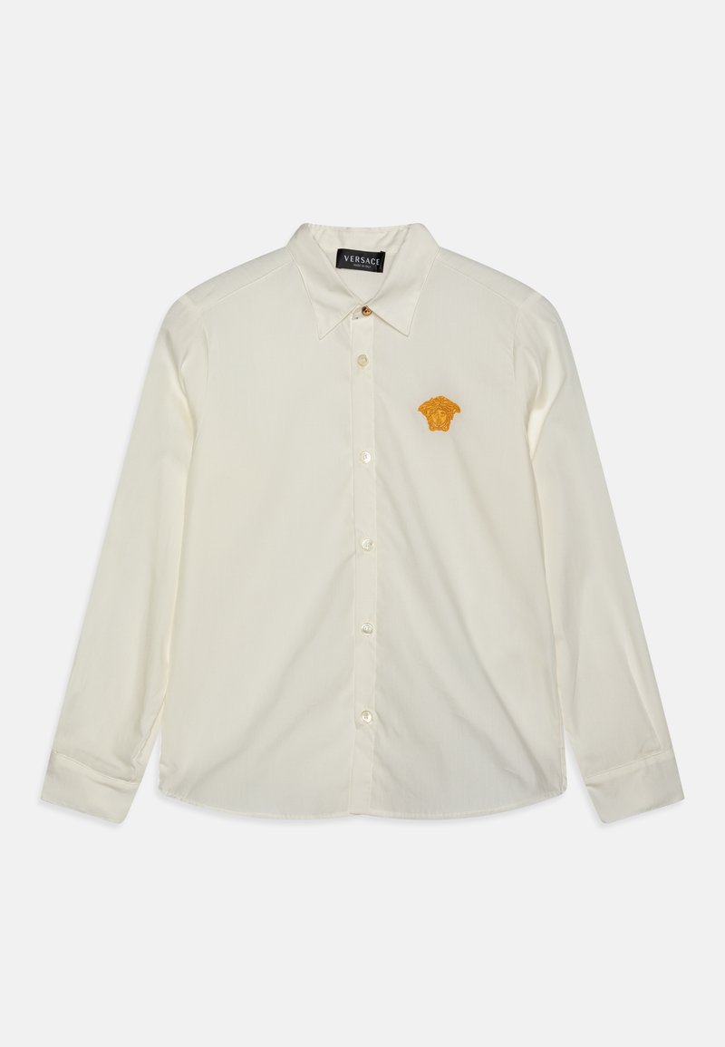 Camicia a maniche lunghe con bottoni in tessuto crema, con colletto a punta, caratterizzata da un emblema di Medusa ricamato in oro sul lato sinistro del petto.