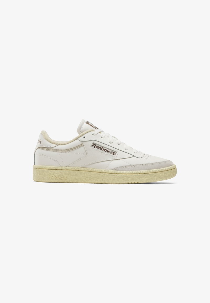 Balti ādas tenisi ar krēmīgu gumijas zoli. Uz sāniem ir Reebok logo un teksturēti akcenti pie purna un papēža.