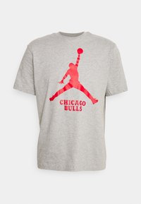 Camiseta de algodón gris con un gráfico rojo de una figura saltando y el texto "CHICAGO BULLS" debajo, de mangas cortas y con cuello redondo.
