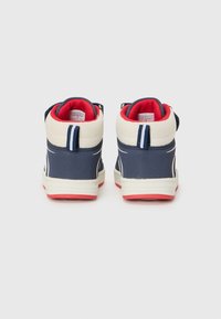 Les baskets montantes présentent un extérieur bleu marine, des accents blancs et rouges, avec un dos texturé et un col rembourré pour le confort.