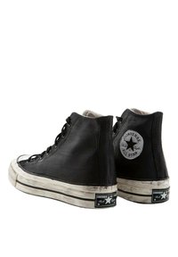 Czarne, wysokie trampki z płótna z gumową podeszwą, białymi krawędziami i okrągłą łatą logo na zewnętrznej pięcie. Noszona, chropowata faktura.