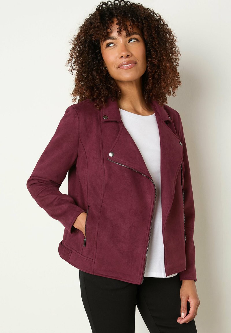 Veste de moto en faux suède bourgogne avec une fermeture éclair diagonale, des détails à bouton-pression et deux poches latérales zippées. Manches longues et coupe ajustée.