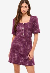 Vestito viola a maniche corte con trama strutturata, scollo quadrato e righe con accenti dorati; cinque bottoni sul davanti.