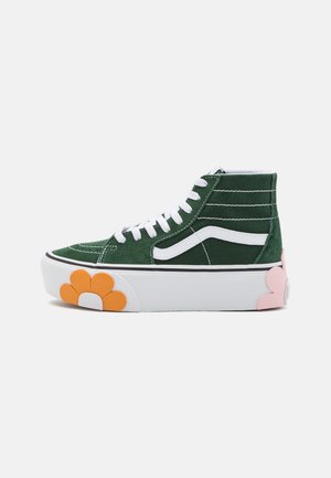 Zielony sneaker za kostkę z białymi sznurowadłami i paskiem, gruba biała podeszwa ozdobiona pomarańczowymi i różowymi kwiatowymi wzorami.
