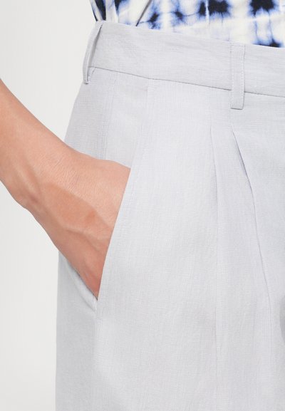 Pantalonii pliati gri deschis au un design elegant, cu un buzunar lateral. Materialul are un model texturat subtil.