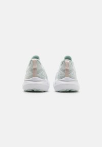 Lysegrøn nett sneakers med et teksturert design, hvit mellomsåle og en blek rosa hæltab. Kjennetegnet av sin minimalistiske stil og demping.
