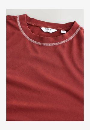 Rotes T-Shirt aus weichem Stoff, mit lässiger Passform, Rundhalsausschnitt mit kontrastierenden Nähten und einem kleinen Etikett am Ausschnitt.