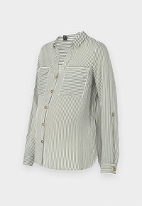Blusa premaman a maniche lunghe verde e bianca a righe verticali con bottoni e tasche sul petto anteriore su sfondo uniforme.