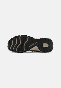 Semelle striée noire et beige d'une chaussure de randonnée Columbia avec des motifs de grip et le logo visibles au bas.