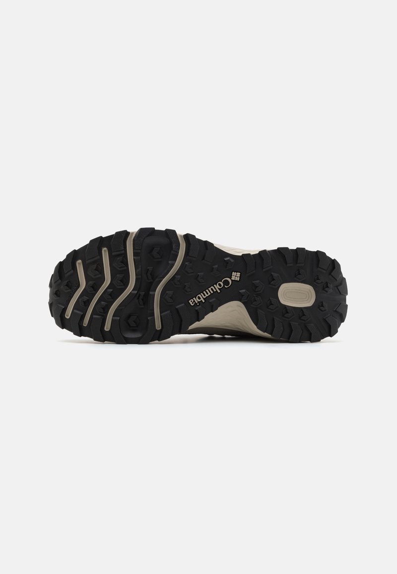 Gummierte schwarze und beige Sohle eines Columbia-Outdoorschuhs mit sichtbaren Grip-Mustern und Logo auf der Unterseite.