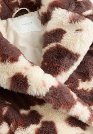 Cappotto in finta pelliccia con stampa a macchie di mucca in crema e marrone. Texture morbida e pelosa con toppe di colore a contrasto e foderato in raso. Etichetta del marchio all'interno.