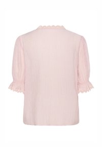 Blouse rose clair avec manches courtes bouffantes, tissu texturé, et détails festonnés au niveau de l'encolure et des bords des manches. Vue de dos montrée.