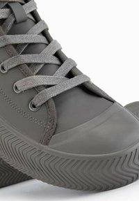 Šedé vysoké tenisky vyrobené z hladkého syntetického materiálu, s texturovanými gumovými podešvemi a šedými tkaničkami, s designem zaoblené špičky.